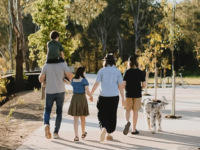 A family walking under a tree lined street.